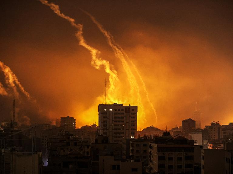 Rauch steigt aus Gaza vor einem von Feuer erleuchteten Nachthimmel auf, nachdem Israels Armee weitere Luftangriffe gegen die Hamas-Terroristen geflogen hat. 
