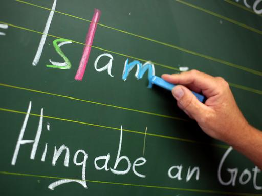 Ein Religionslehrer schreibt während des islamischen Religionsunterrichts an der Tafel.
