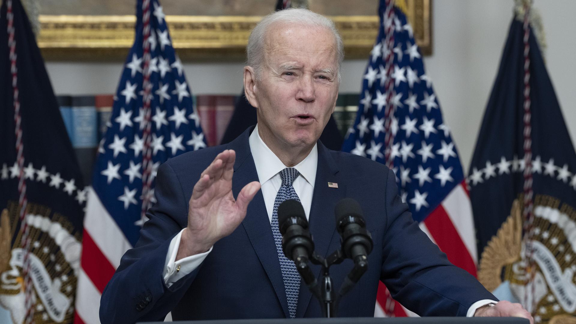 US-Präsident Joe Biden macht eine beschwichtige Geste an einem Rednerpult, hinter ihm die amerikanische Flagge.