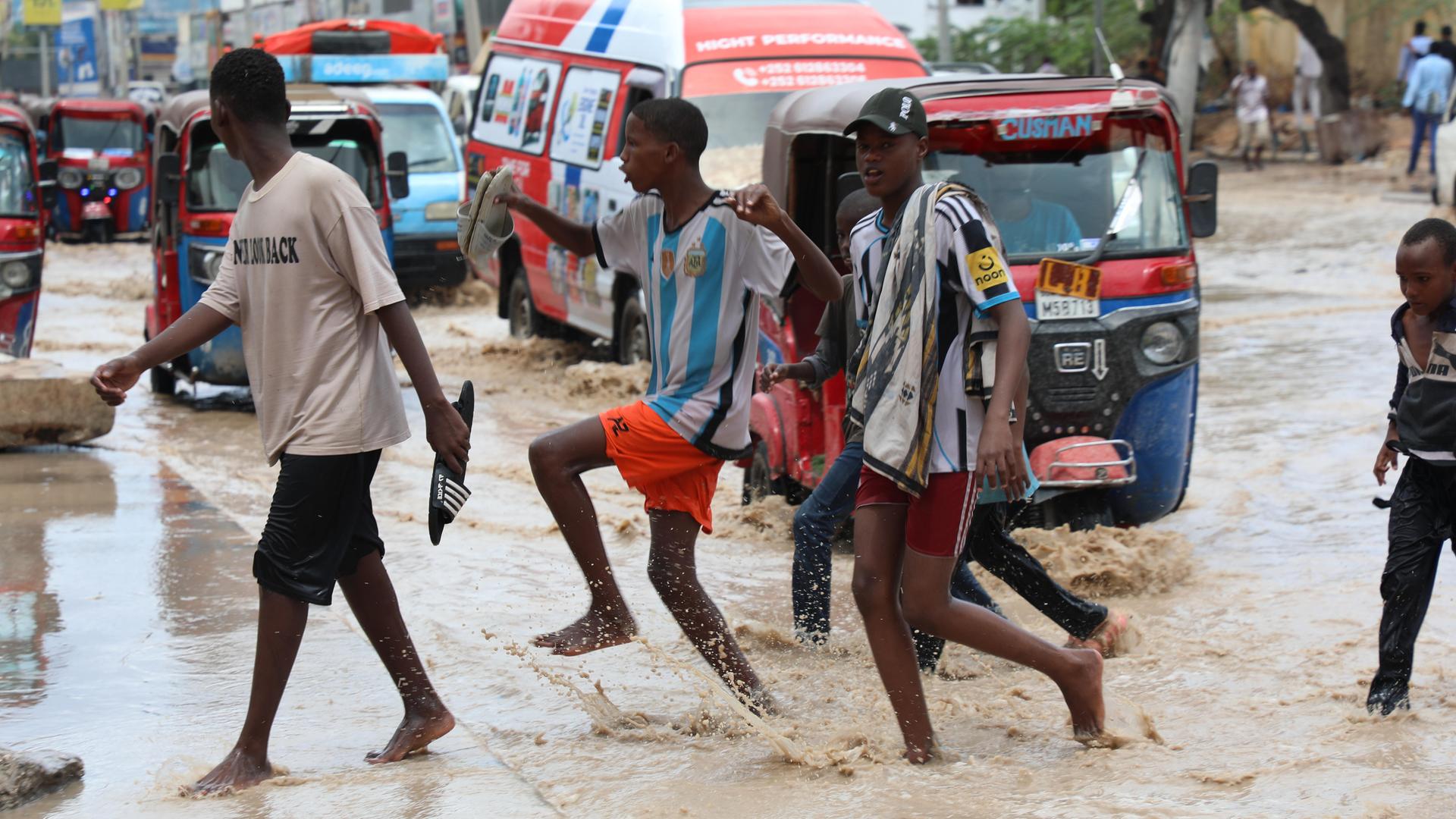 Junge Männer überqueren eine Straße in Mogadischu nach heftigen Regenfällen. Junge Männer überqueren eine Straße in Mogadischu nach heftigen Regenfällen.