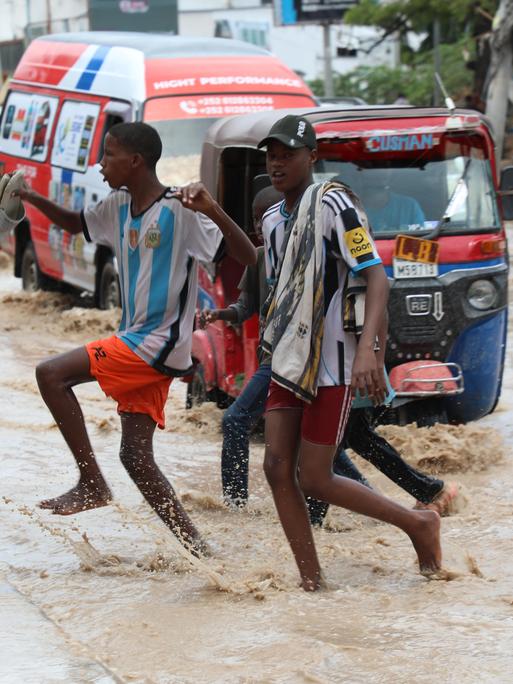 Junge Männer überqueren eine Straße in Mogadischu nach heftigen Regenfällen. Junge Männer überqueren eine Straße in Mogadischu nach heftigen Regenfällen.