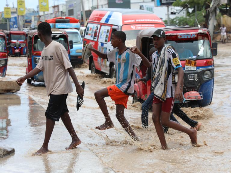 Junge Männer überqueren eine Straße in Mogadischu nach heftigen Regenfällen. Junge Männer überqueren eine Straße in Mogadischu nach heftigen Regenfällen.