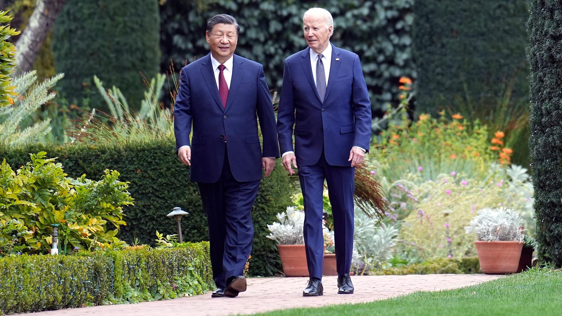 Biden und Xi gehen nebeneinander durch einen Park.