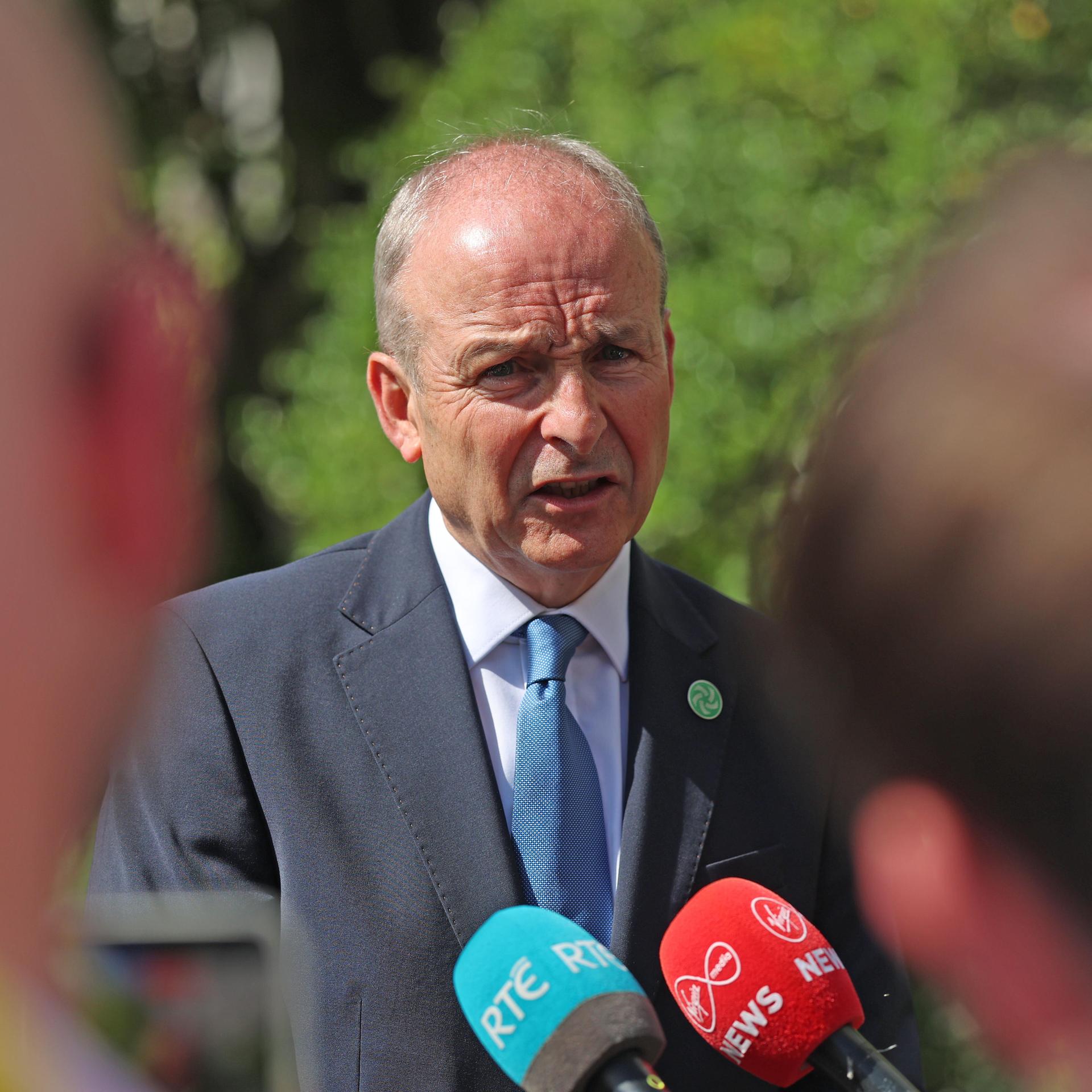 Der irische Regierungschef Martin steht vor Journalisten mit Mikrofonen und spricht.