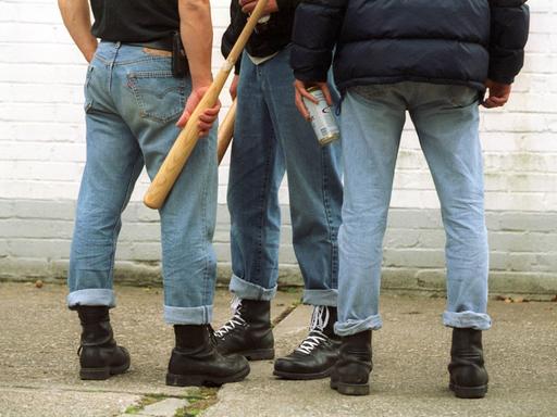 Drei Männer mit Jeans, Bomberjacken und Springerstiefel stehen in einer Gruppe zusammen. (Symbolfoto)