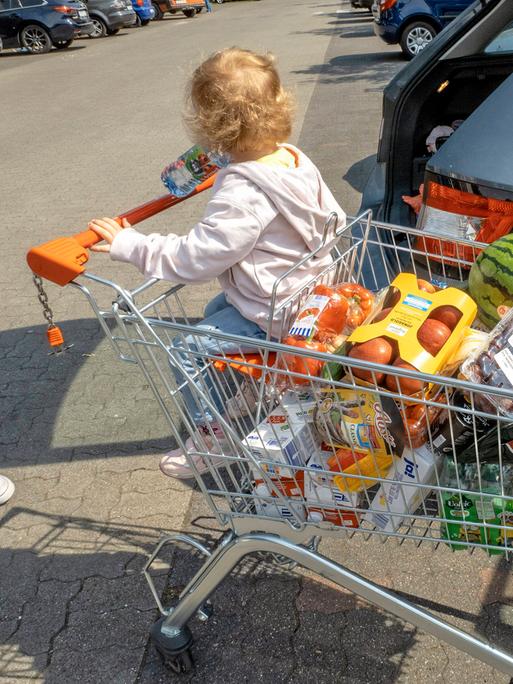 Ein voller Einkaufswagen samt Kind
