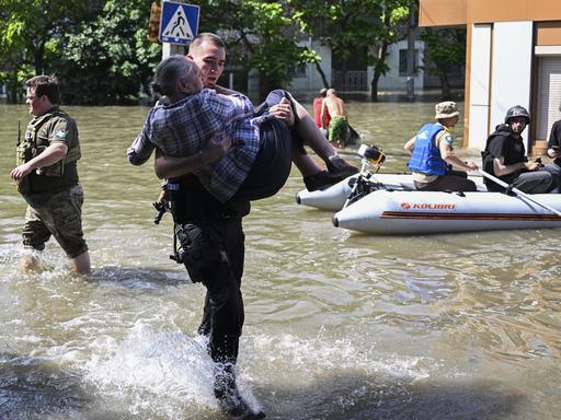 Ein Soldat trägt eine ältere Frau aus den Fluten.