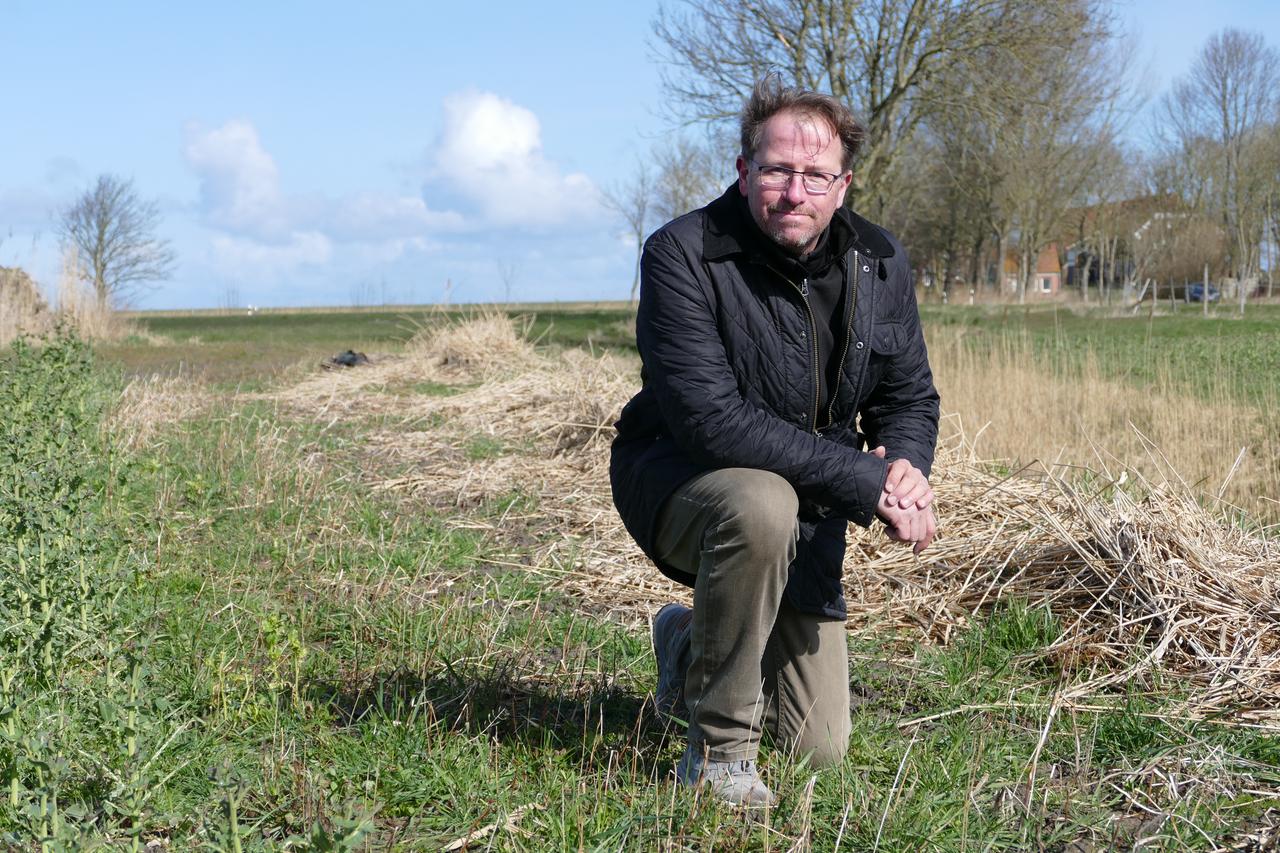 Carl Noosten kniet auf seinem Ackerland