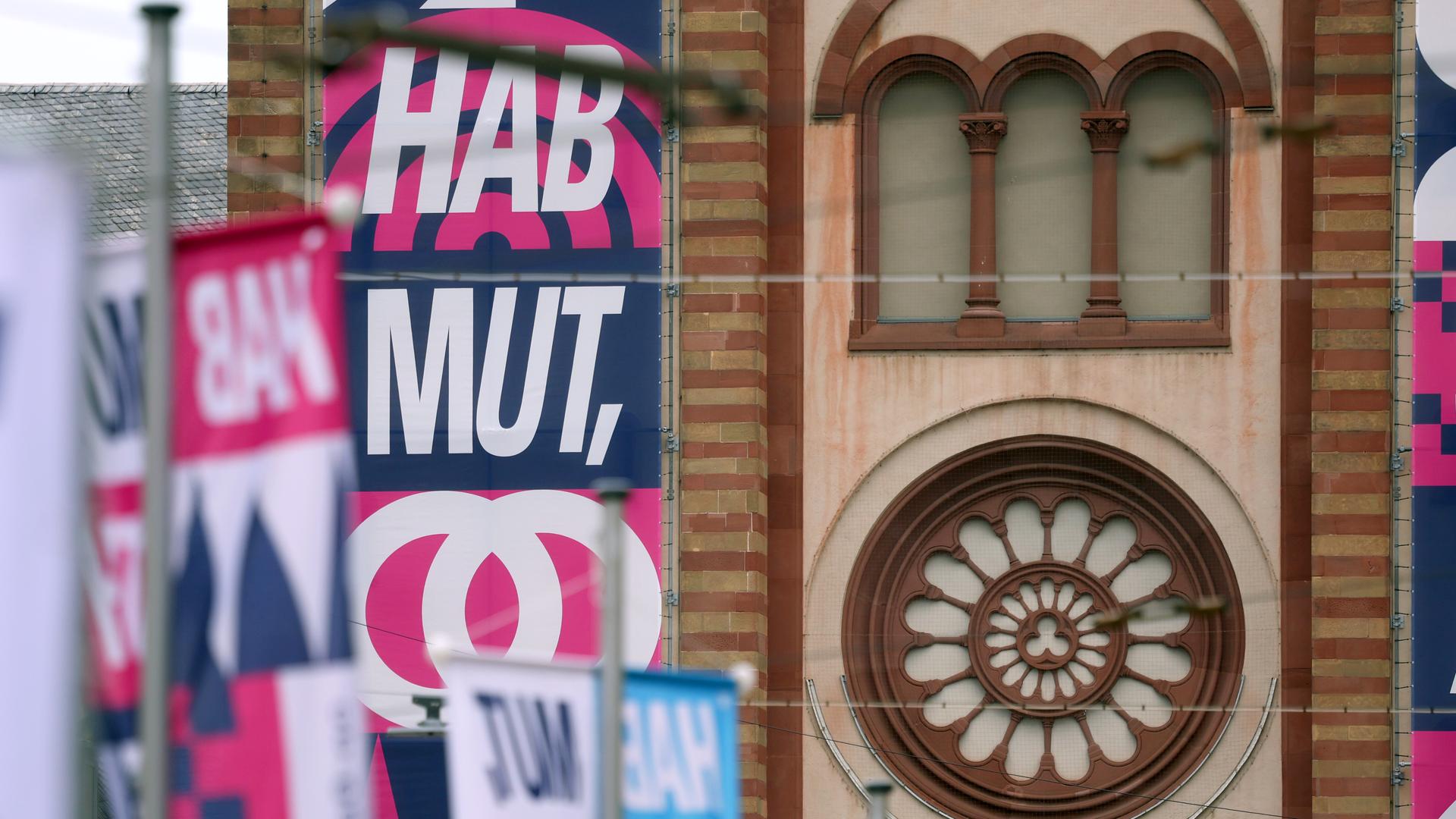 Der Slogan "HAB MUT, STEH AUF!" steht auf Bannern an den Türmen des Kiliansdoms in Würzburg.