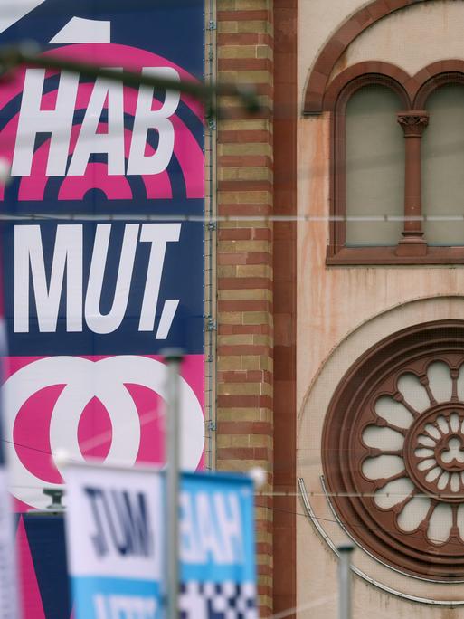Der Slogan "HAB MUT, STEH AUF!" steht auf Bannern an den Türmen des Kiliansdoms in Würzburg.