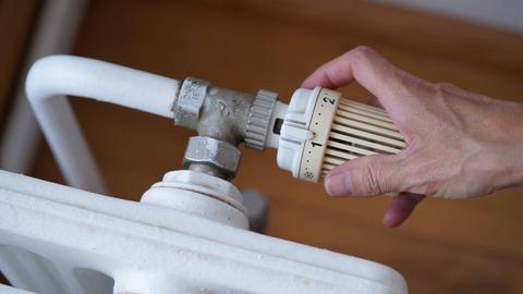 Eine Hand regelt eine Heizung, die auf Stufe eins steht