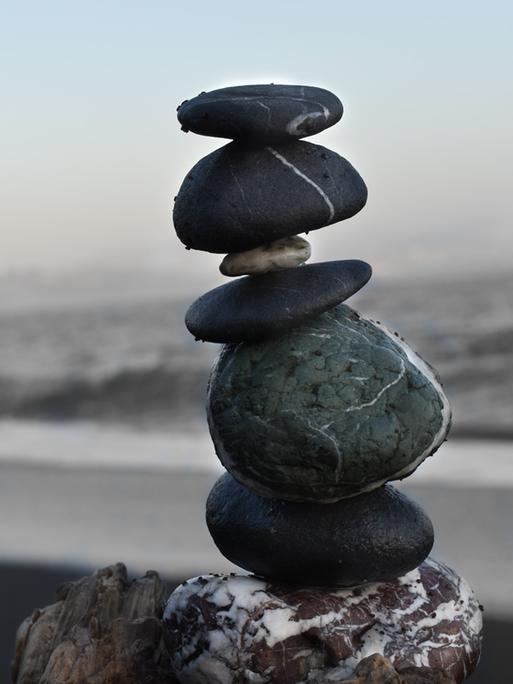 Aufeinander balancierende Steine bilden einen kleinen Turm an einem Strand. 