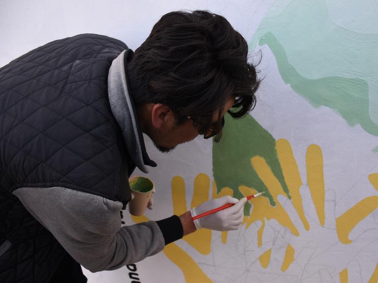 Ein afghanischer Künstler malt mit dem Pinsel ein Wandgemälde. 