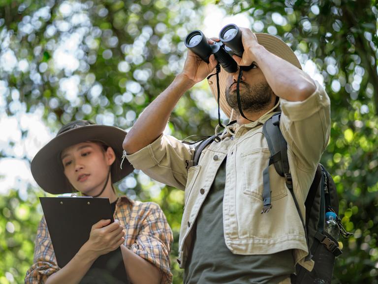 Zwei Ornithologen mit Fernglas und Kladde zur Aufzeichnung bei der Vogelbeobachtung