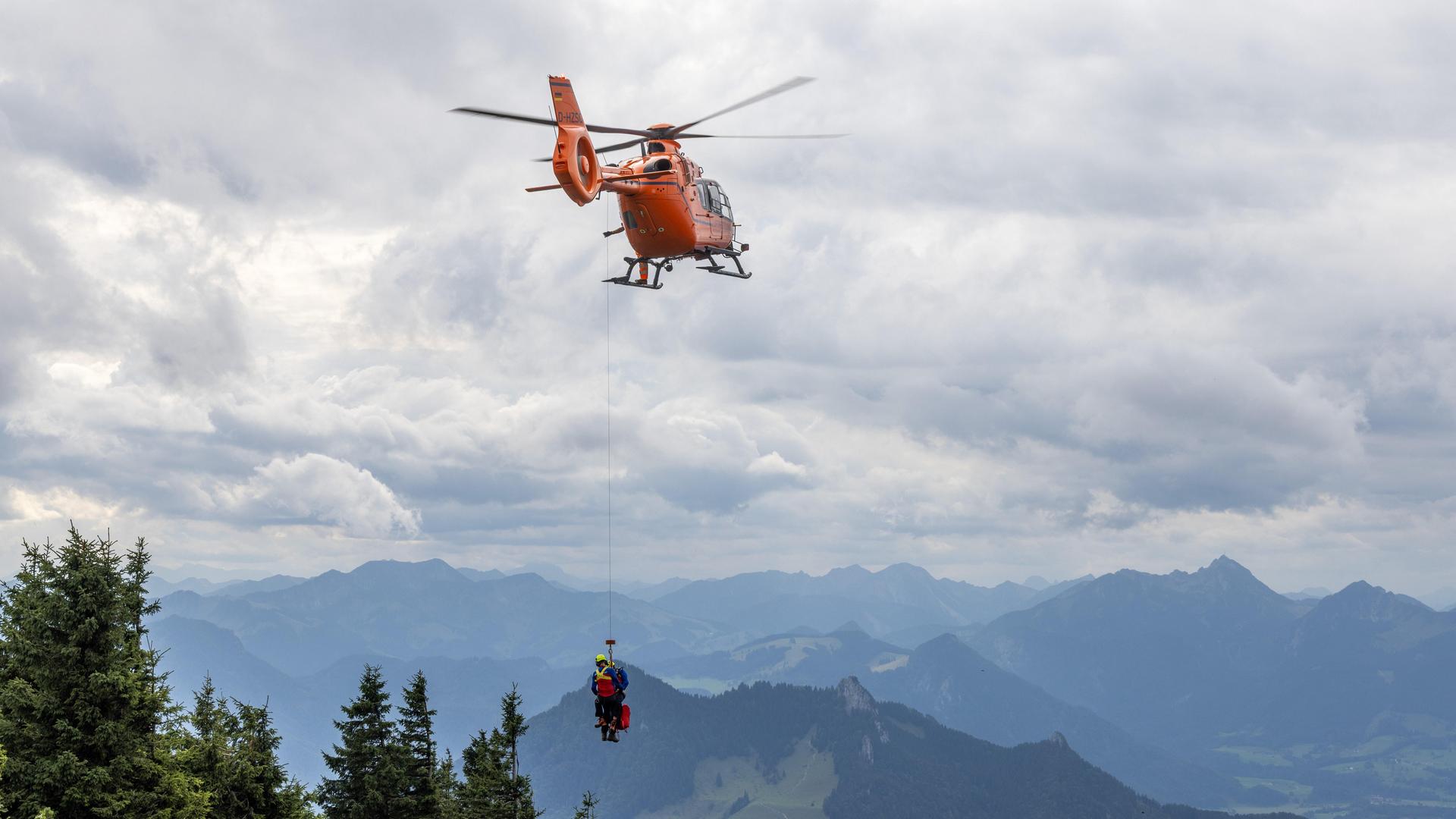 Ein Rettungshubschrauber in den Alpen, der an einem Seil zwei Personen transportiert. Ein Rettungshubschrauber in den Alpen, der an einem Seil zwei Personen transportiert.
