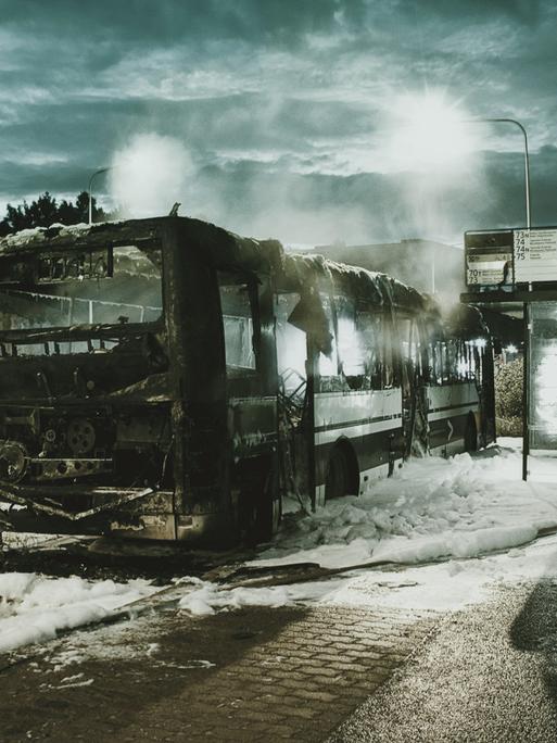 Ein ausgebrannter Autobus steht an einer Bushaltestelle