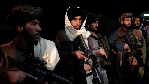 Mit Maschinengewehren bewaffnete Talibankämpfer stehen nebeneinander in einer Reihe.
