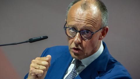 Bundeskanzler Friedrich Merz (CDU) spricht in ein Mikrofon. Er hat seine rechte Hand zur Faust geballt.
