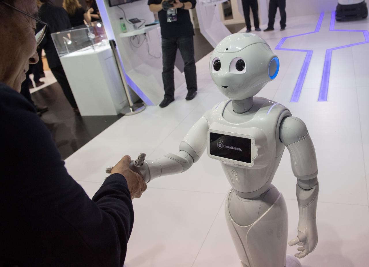 Ein kleiner weißer humnaoider Roboter gibt einem Menschen die Hand.