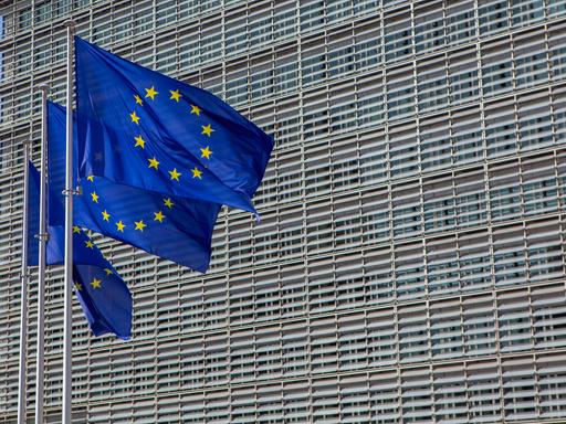 Das Berlaymont-Gebäude in Brüssel, der Sitz der Europäischen Kommission. Davor wehen drei Europafahnen. 