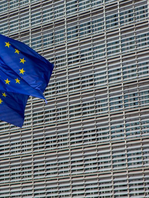 Das Berlaymont-Gebäude in Brüssel, der Sitz der Europäischen Kommission. Davor wehen drei Europafahnen. 