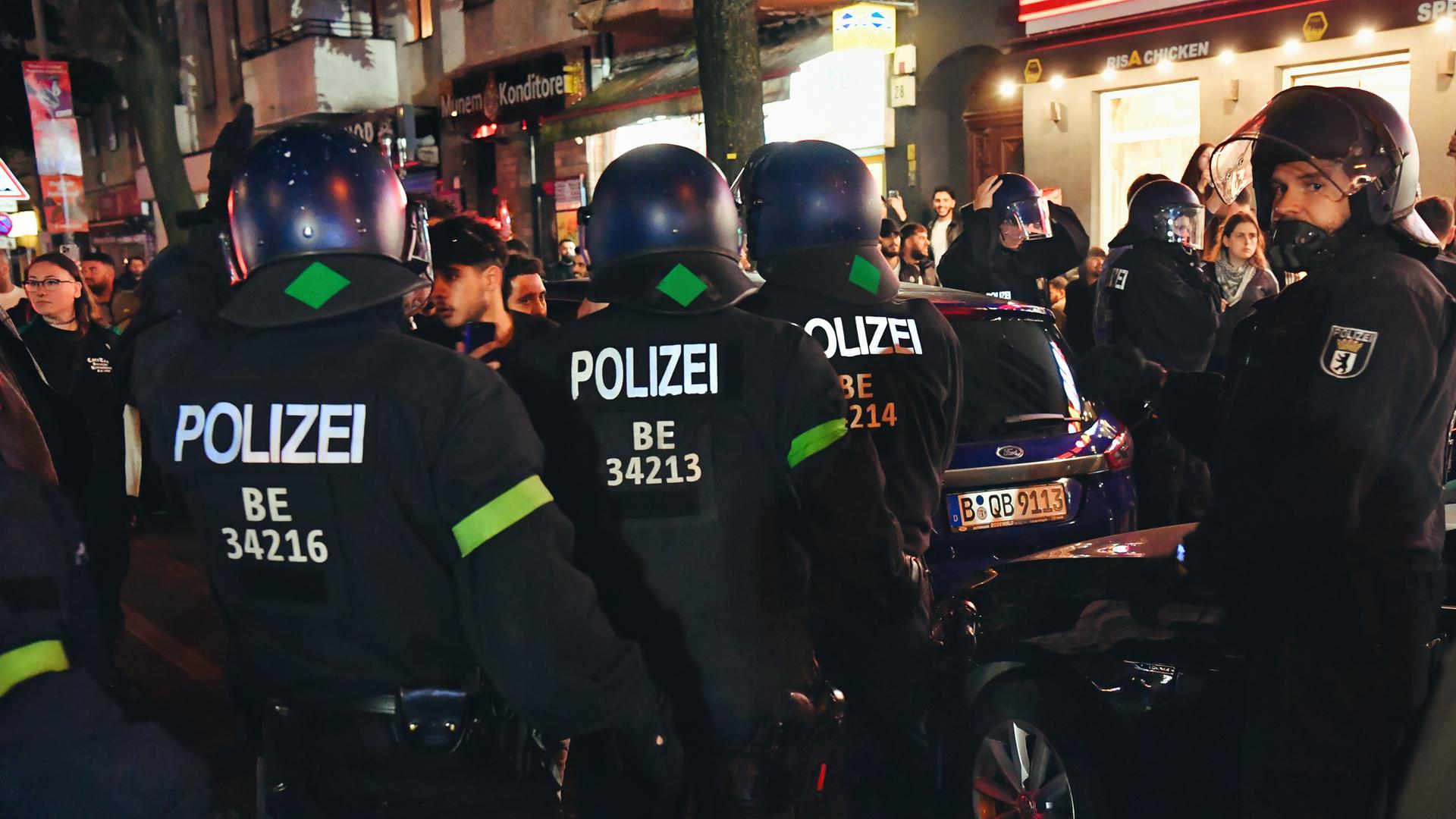 Polizeibeamte stehen am Mittwochabend auf der Sonnenallee in Neukölln vor einer größeren Menschenmenge. Polizeibeamte stehen am Mittwochabend auf der Sonnenallee in Neukölln vor einer größeren Menschenmenge.