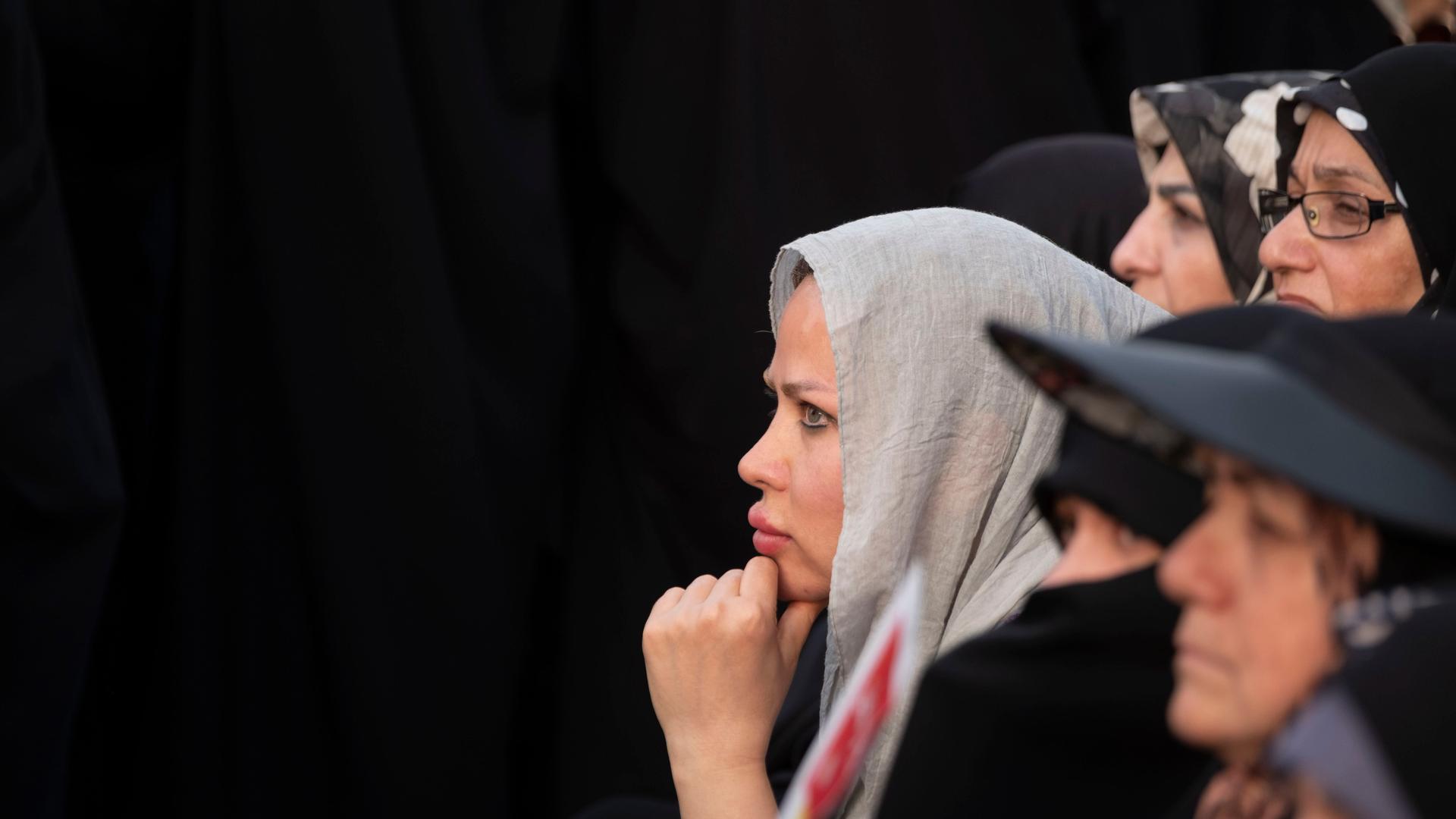 Verschiedene Frauen im Profil stehen vor einer schwarzen Wand.