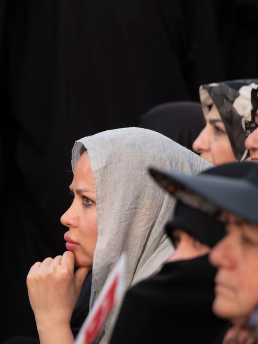 Verschiedene Frauen im Profil stehen vor einer schwarzen Wand.