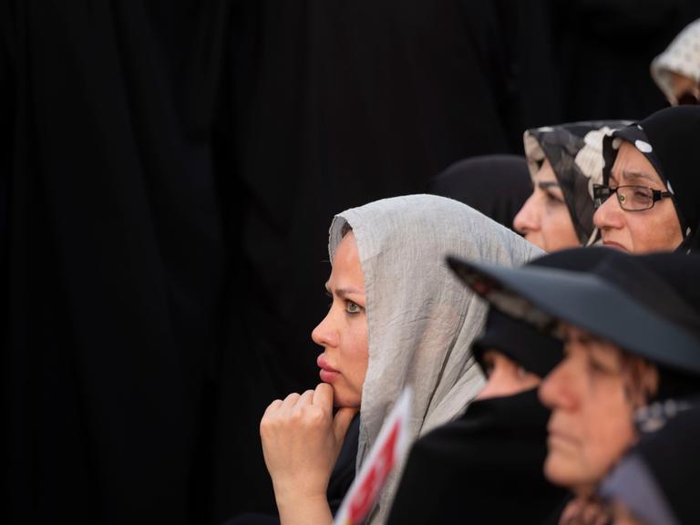 Verschiedene Frauen im Profil stehen vor einer schwarzen Wand.
