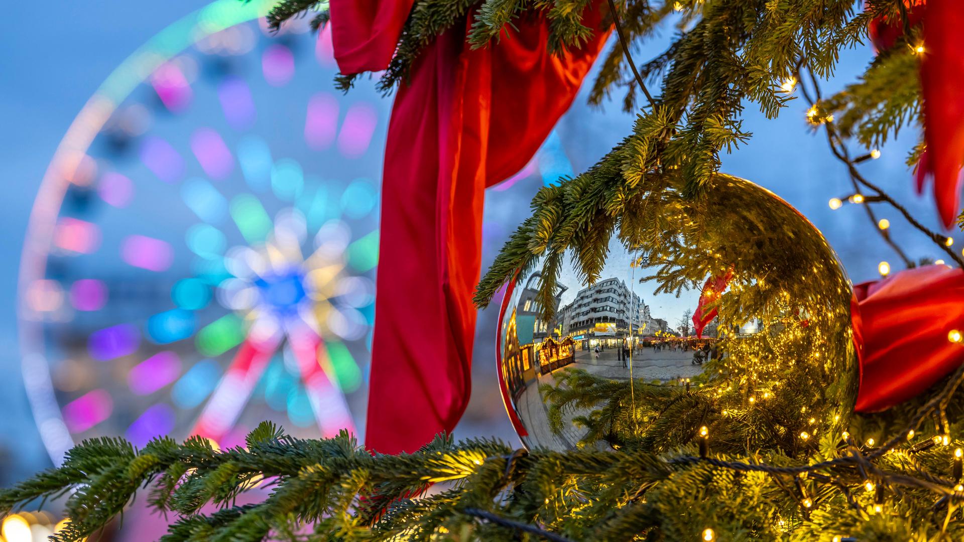 Buden spiegeln sich in einer Weihnachtskugel. Im Hintergrund: ein Riesenrad. Buden spiegeln sich in einer Weihnachtskugel. Im Hintergrund: ein Riesenrad.