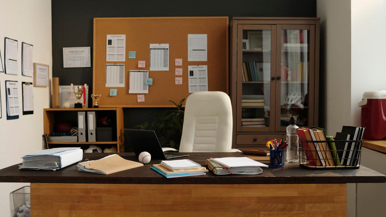 Ein Büro mit großem hölzernen Schreibtisch und Schränken voller Aktenordner und Pokale.