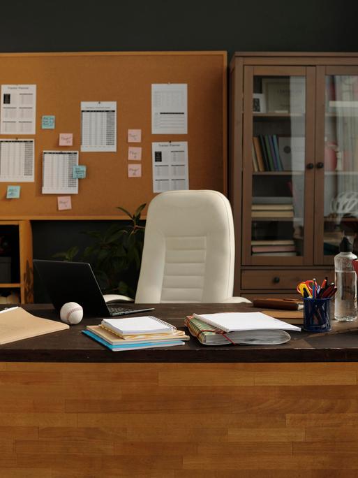 Ein Büro mit großem hölzernen Schreibtisch und Schränken voller Aktenordner und Pokale.