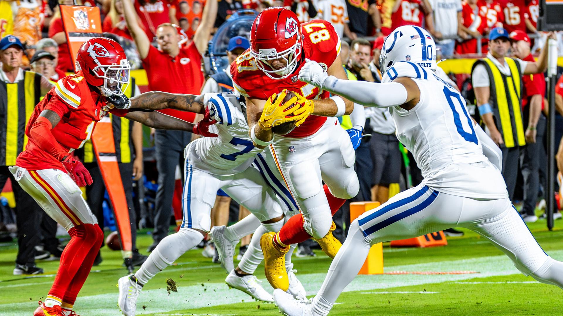 Tight End Travis Kelce von den Kansas City Chiefs springt mit dem Football zur Ziellinie, während gegenerische Teammitglieder versuchen ihn von allen Seiten zu stoppen. Tight End Travis Kelce von den Kansas City Chiefs springt mit dem Football zur Ziellinie, während gegenerische Teammitglieder versuchen ihn von allen Seiten zu stoppen.