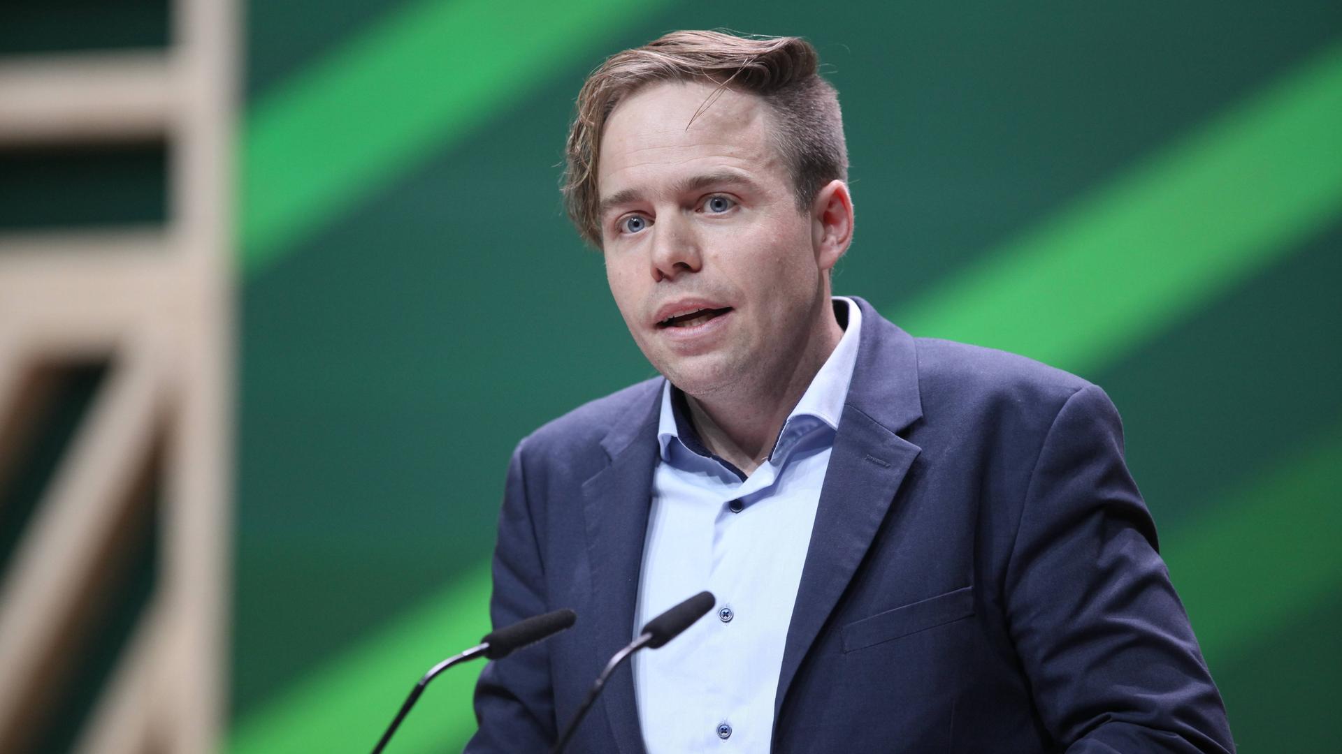 Rasmus Andresen spricht an zwei Mikrofonen vor einem grünen Hintergrund. Rasmus Andresen spricht an zwei Mikrofonen vor einem grünen Hintergrund.