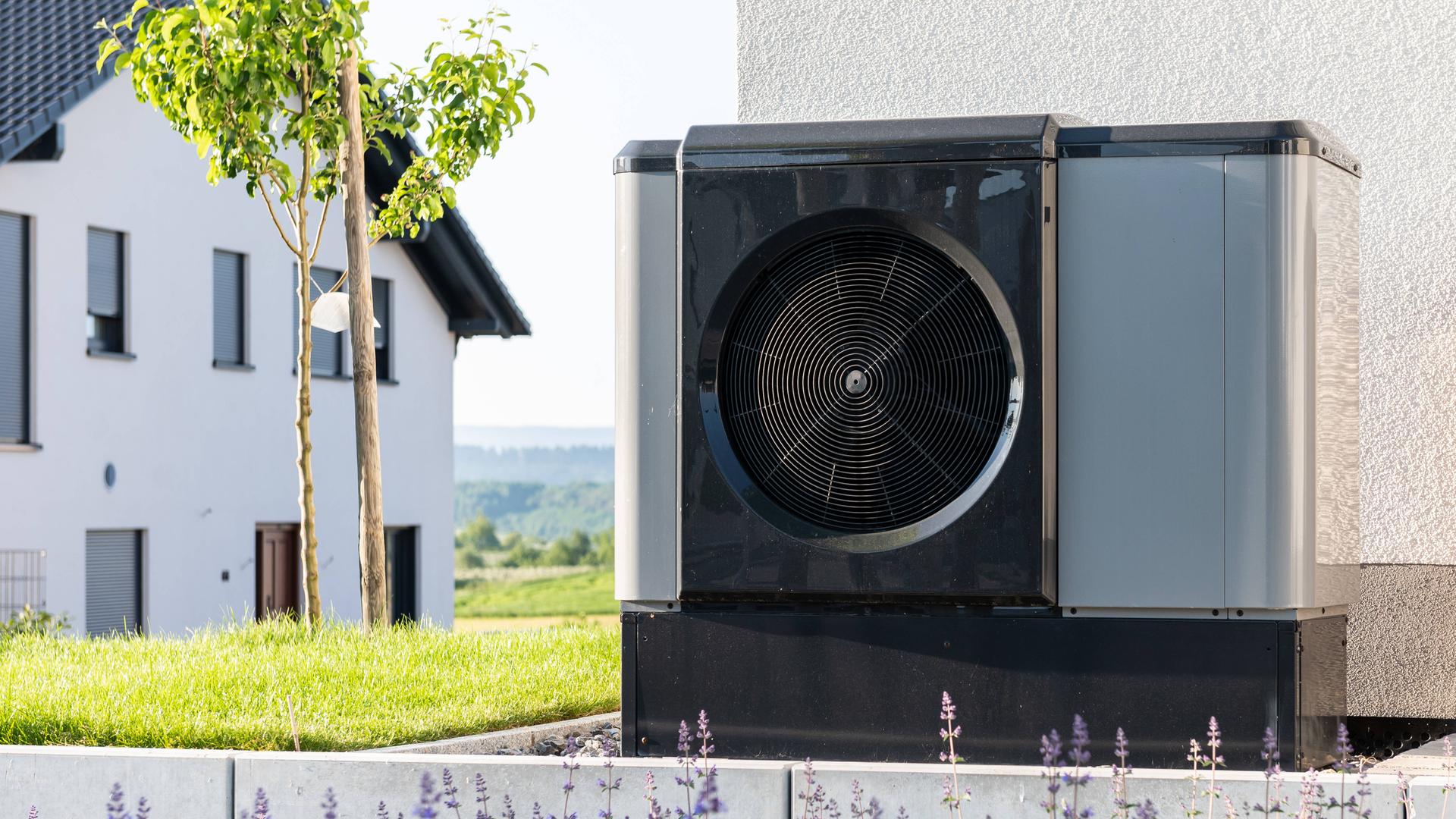 Eine Wärmepumpe steht im Garten eines Einfamilienhauses.