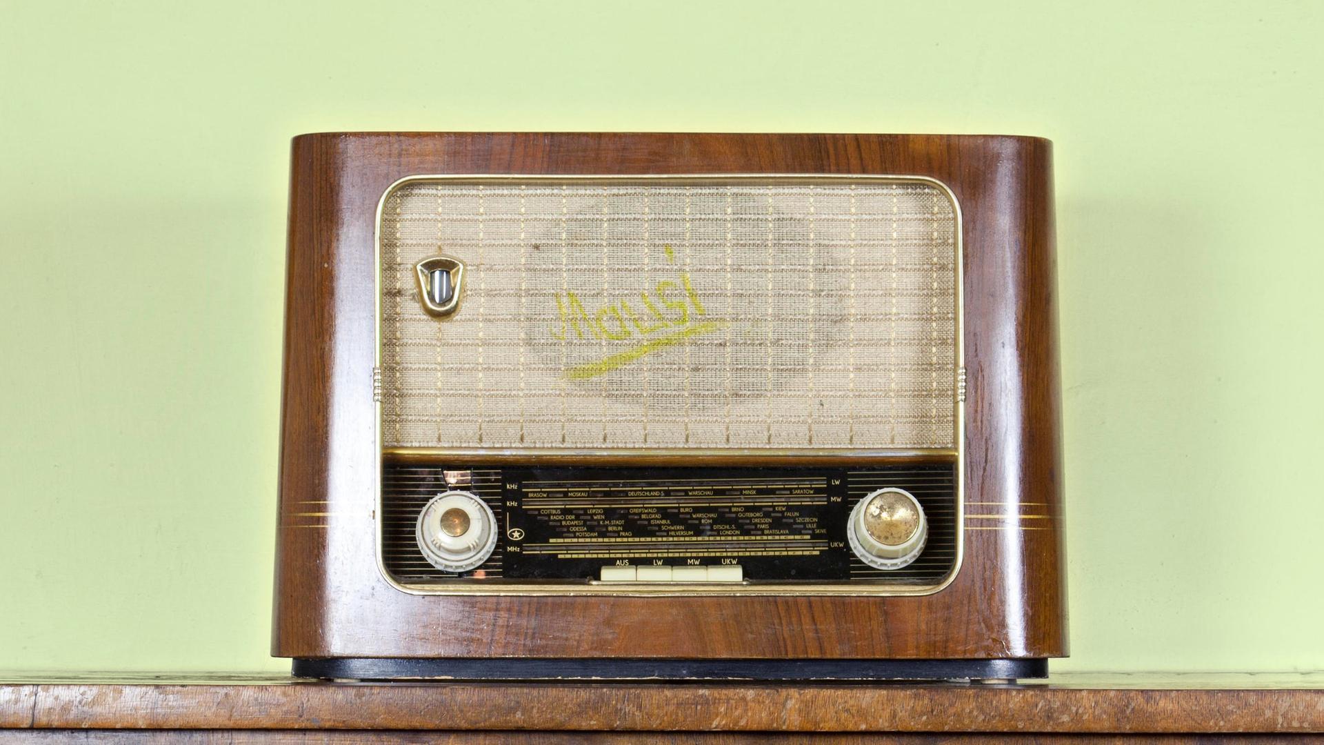 Ein nostalgisches Röhrenradio steht auf einer Holzkommode. 