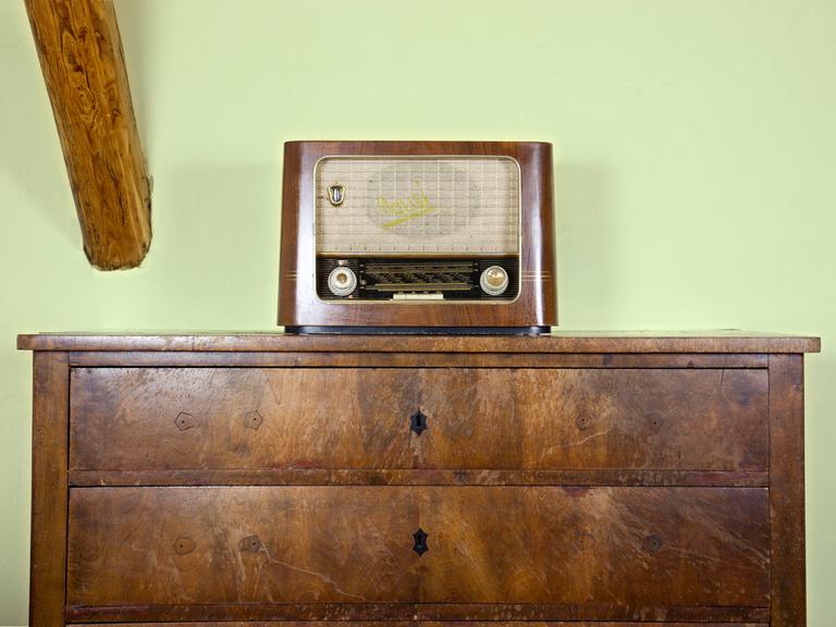 Ein nostalgisches Röhrenradio steht auf einer Holzkommode. 