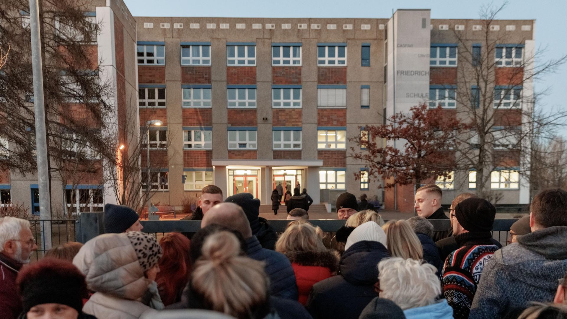 Bürger stehen vor dem verschlossenen Zugang zu Schule "Caspar David Friedrich". Bürger stehen vor dem verschlossenen Zugang zu Schule "Caspar David Friedrich".