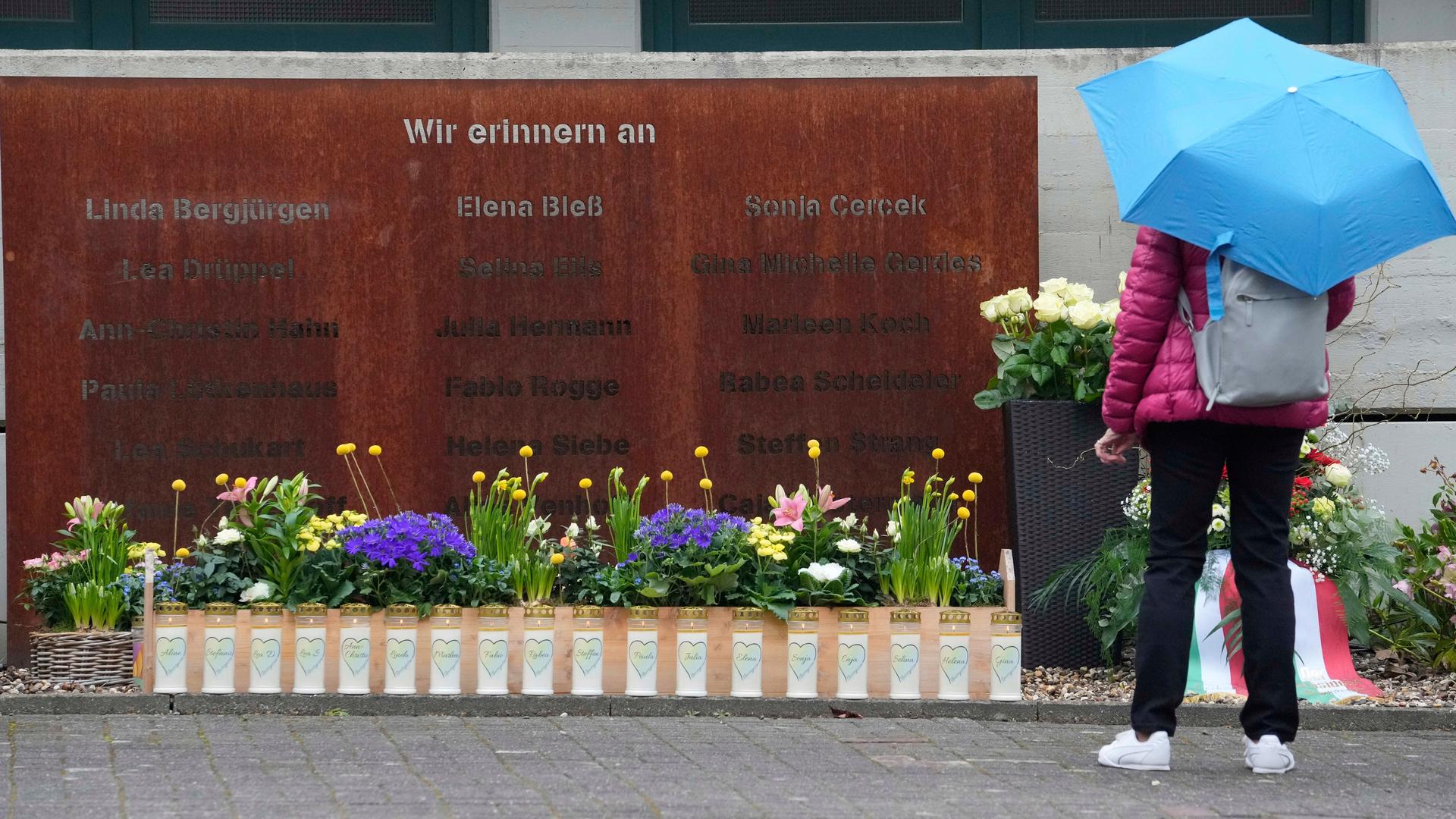 Eine Frau steht vor einer Gedenktafel. An der Tafel stehen die Namen der Menschen, die bei dem Flugzeug-Absturz vor 10 Jahren ums Leben kamen.