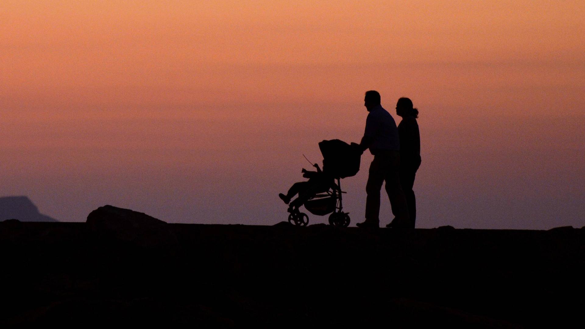 Ein Pärchen mit Kinderwagen geht in der Abenddämmerung auf Kreta spazieren