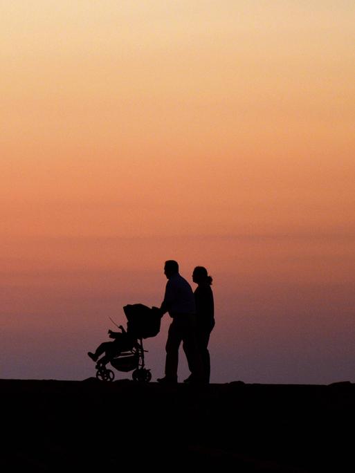 Ein Pärchen mit Kinderwagen geht in der Abenddämmerung auf Kreta spazieren