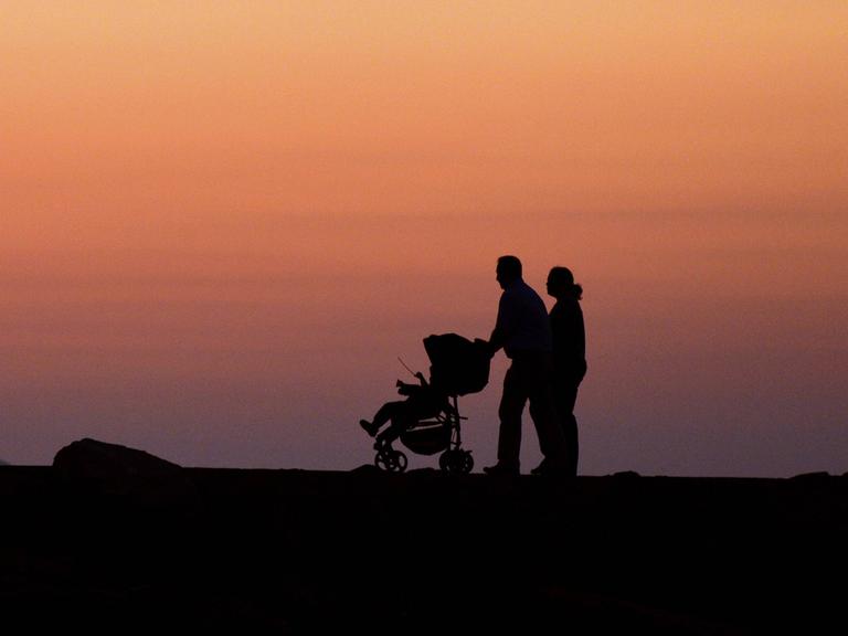Ein Pärchen mit Kinderwagen geht in der Abenddämmerung auf Kreta spazieren