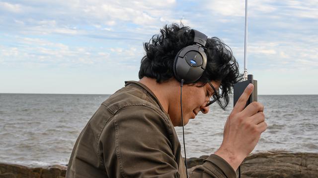 Profil eines jungen Mannes mit Kopfhörern am Ufer des Río de la Plata, Uruguay