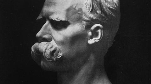 Weiße Büste von Friedrich Nietzsche auf schwarzem Hintergrund.