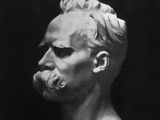 Weiße Büste von Friedrich Nietzsche auf schwarzem Hintergrund.