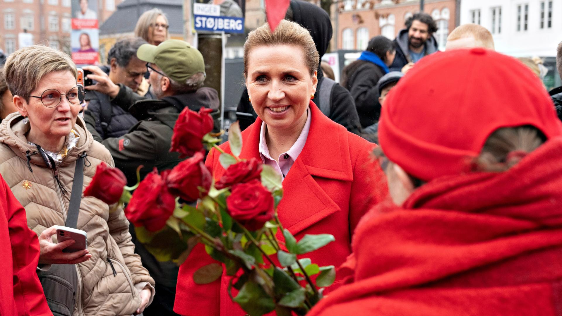 Dänemarks Ministerpräsidentin Mette Frederiksen am Wahltag in Aalborg. Sie trifft Anhänger und hat einen Strauß Rosen in der Hand.