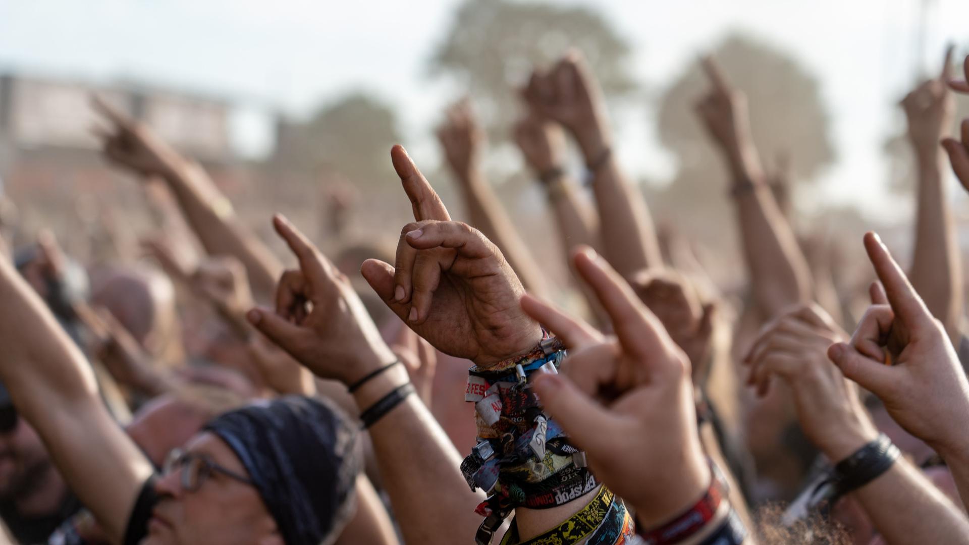 Fans einer Band auf dem Wacken-Festival halten ihre Hände nach oben