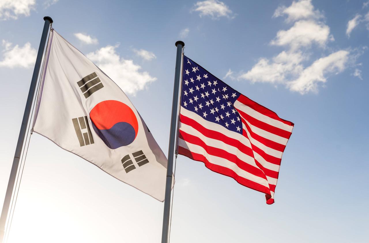 An zwei Fahnenmasten hängen die Flaggen Südkoreas und der USA und wehen im Wind.