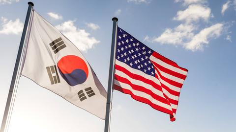 An zwei Fahnenmasten hängen die Flaggen Südkoreas und der USA und wehen im Wind.