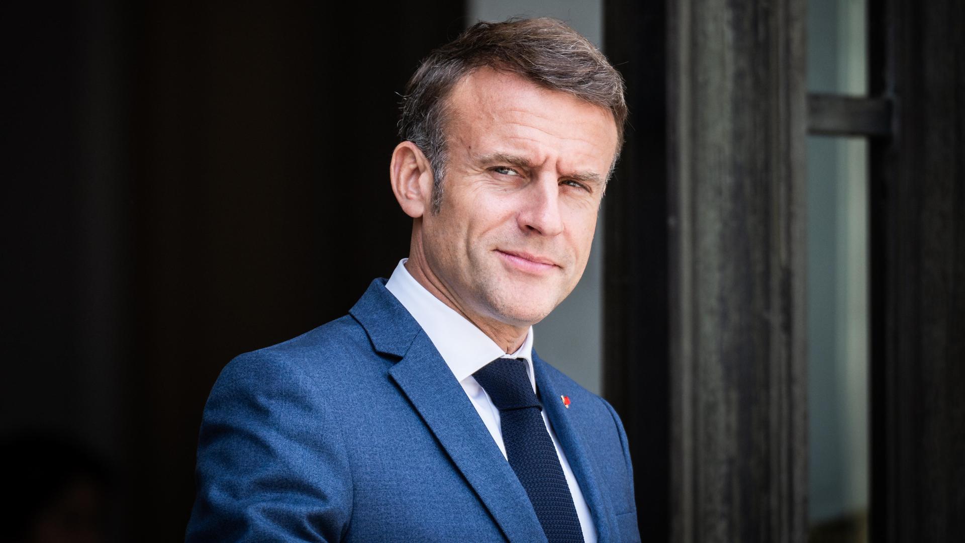 Emmanuel Macron lächelt ernst aber verschmitzt in die Kamera.
